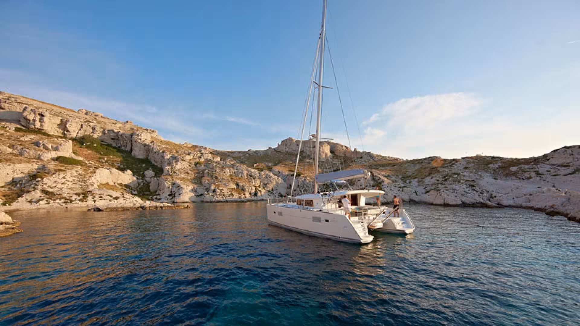 A catamaran anchored near rocky cliffs in the Tavolara Marine Protected Area, perfect for Olbia coastal tours.