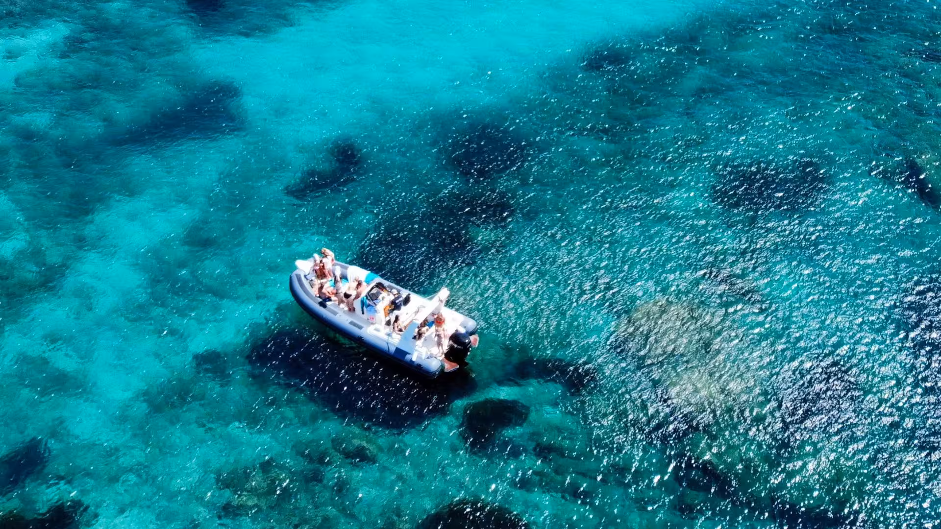Aerial view of a group enjoying a dinghy tour over crystal-clear waters near Tavolara, perfect for Olbia snorkeling adventures.