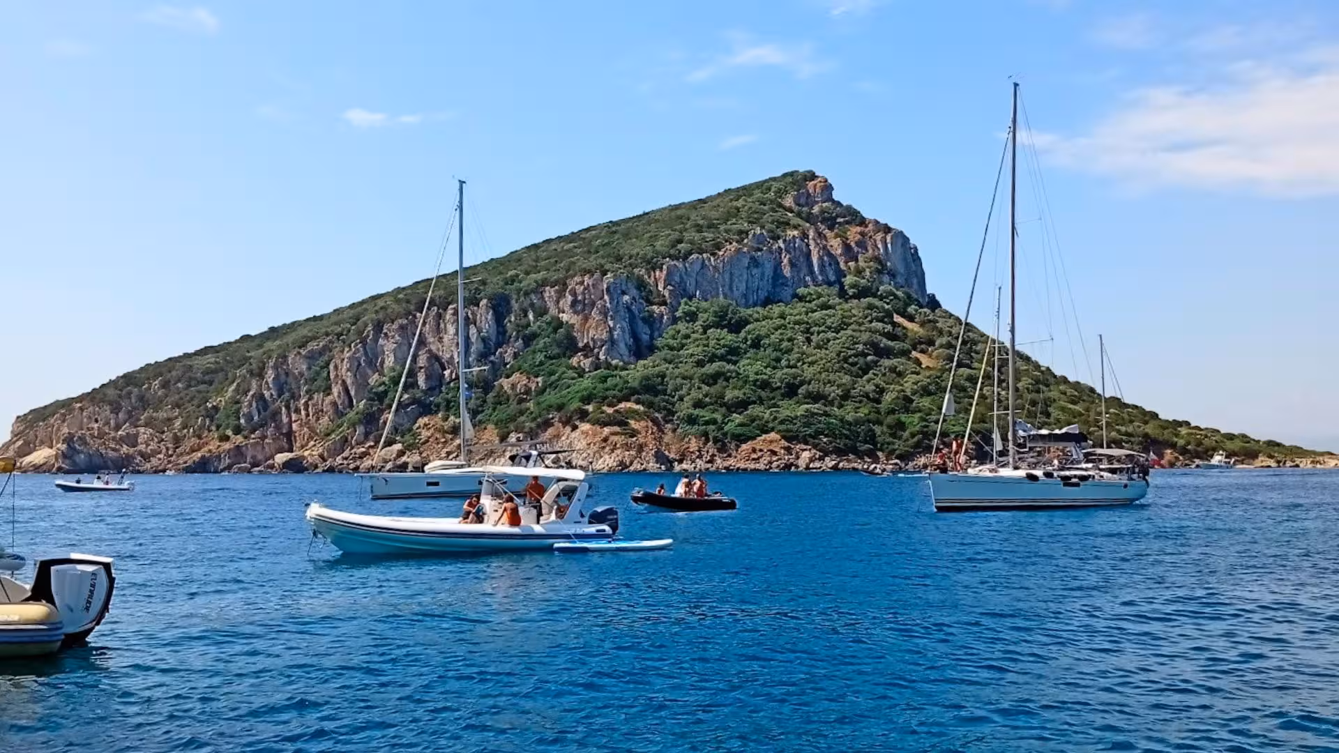 Boats sailing near Capo Figari's rocky coastline, a highlight of the Olbia dolphin watching RIB tour.