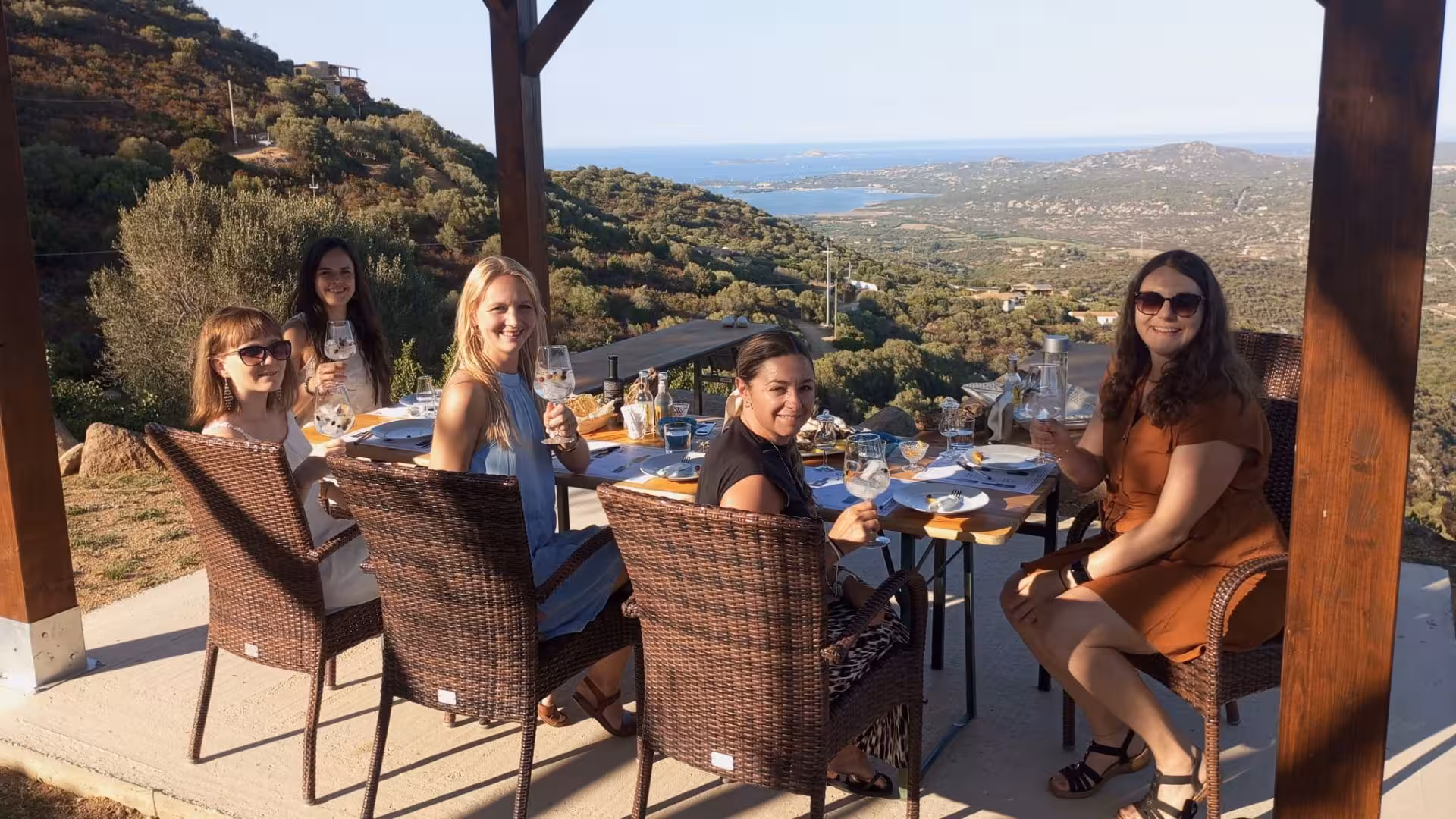 Group of women savoring gin with stunning views at Olbia's gin-making factory tour.