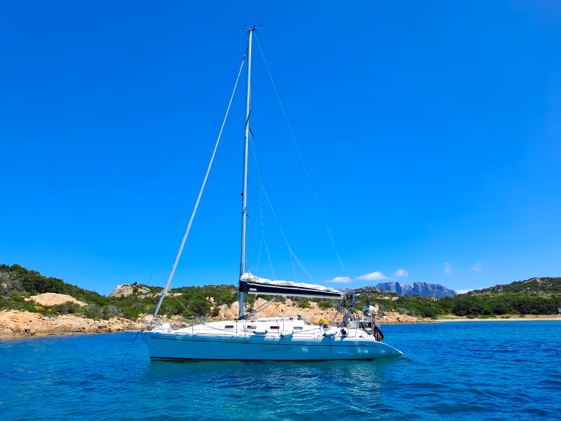 Sailboat anchored in clear blue waters near Tavolara Island on a sunny day, ideal for Olbia sailing tours.