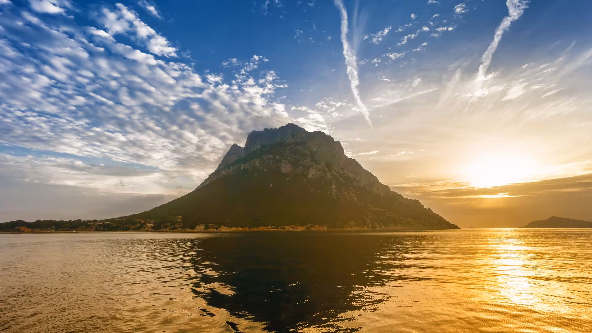 Stunning sunset behind a majestic mountain island, reflecting on calm waters near Olbia.