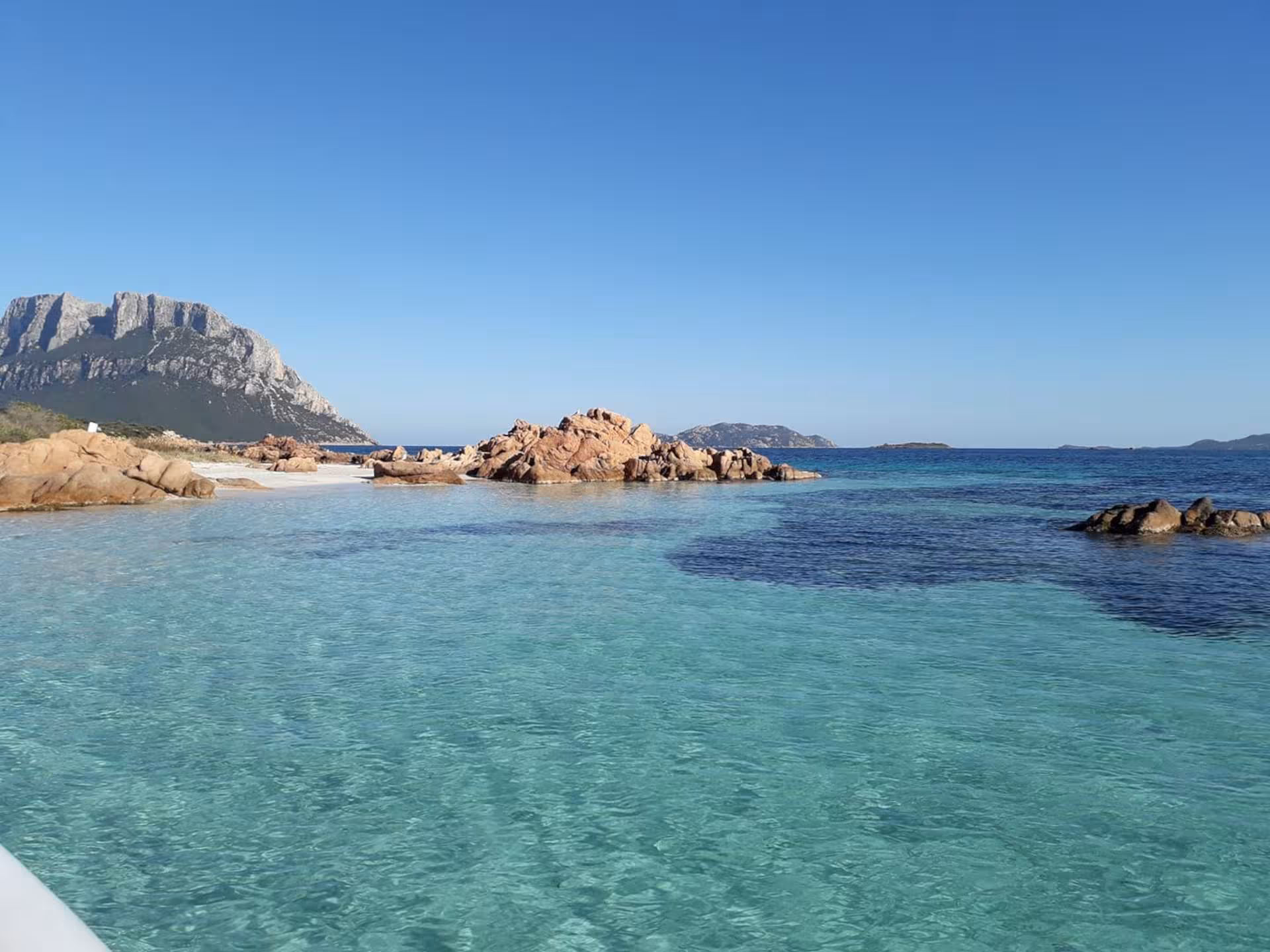 Crystal-clear waters and rocky formations near Tavolara Island, perfect for a serene boat tour experience.
