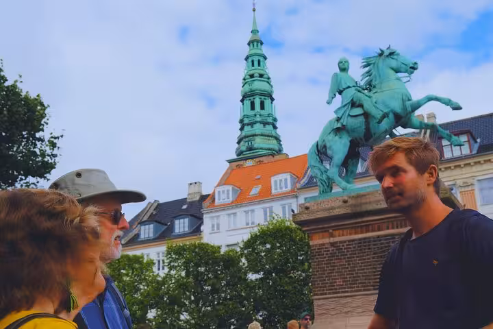 Tourists admire the equestrian statue and spire during a guided tour of Old Copenhagen.