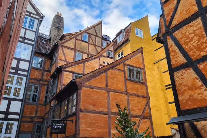 Charming half-timbered buildings in Old Copenhagen's historic district under a vibrant blue sky.