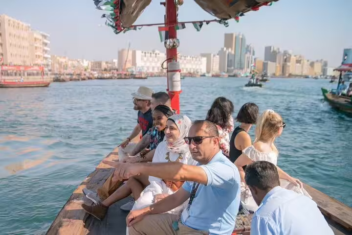 Group of travelers on a traditional abra boat crossing Dubai Creek during a guided walking tour with street food tastings