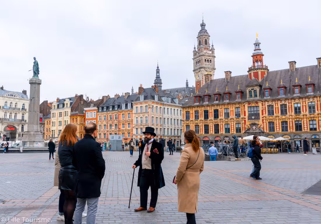 Costumed guide in top hat leading a small group tour on Grand Place square in Old Lille, France
