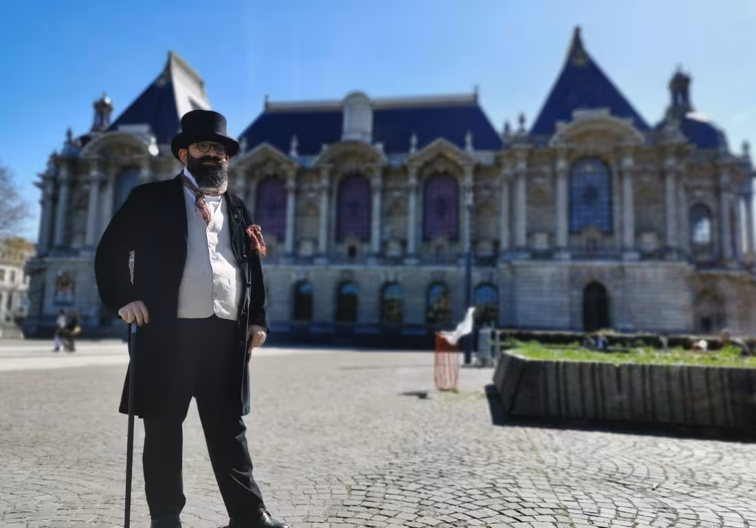 Costumed guide in top hat and Victorian attire with cane stands before ornate Palais des Beaux-Arts in Lille