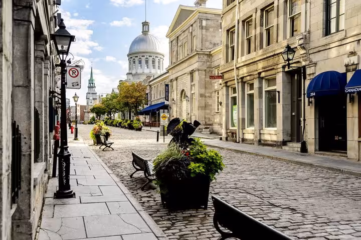 Cobblestone street in Old Montreal with historic stone buildings and Bonsecours Market dome in background