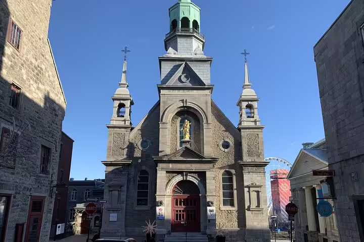 Historic stone church with green copper steeple in Old Montreal on a clear sunny day