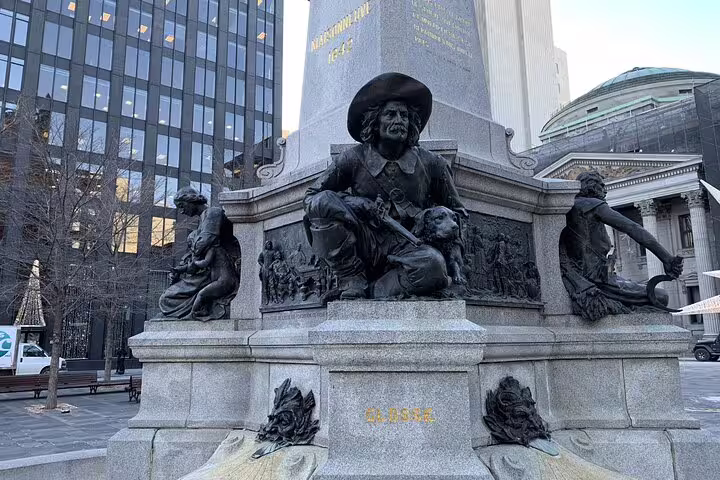 Bronze statue monument at Place d'Armes square in Old Montreal with historic buildings in background