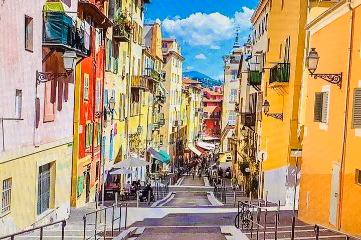 Colorful narrow street in Old Nice with vibrant yellow and red buildings on the French Riviera