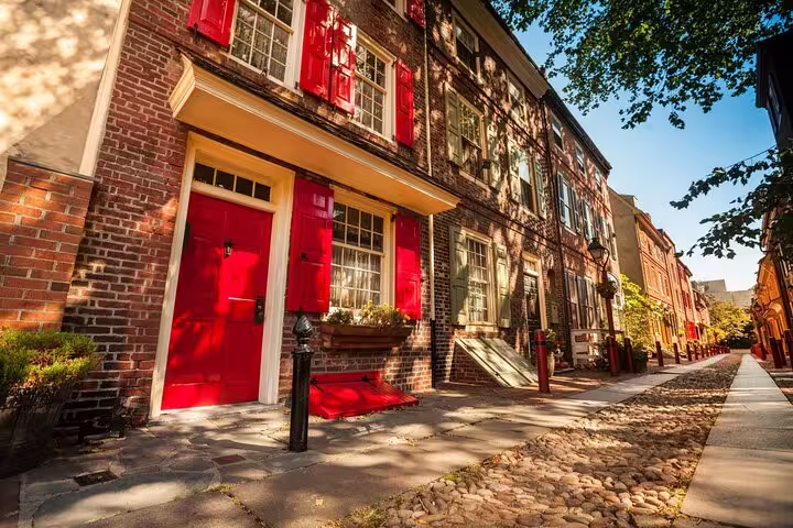 Historic red brick row houses with red doors and shutters on a cobblestone street in Old Philadelphia