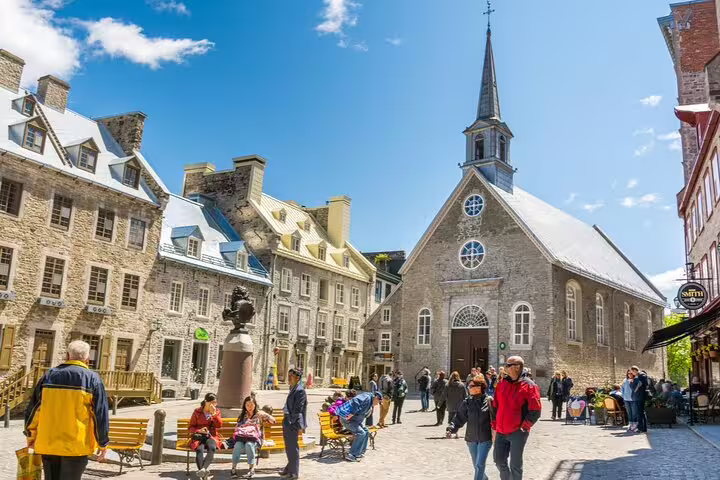 Historic Place-Royale square in Old Quebec City with stone buildings, church steeple, and tourists walking