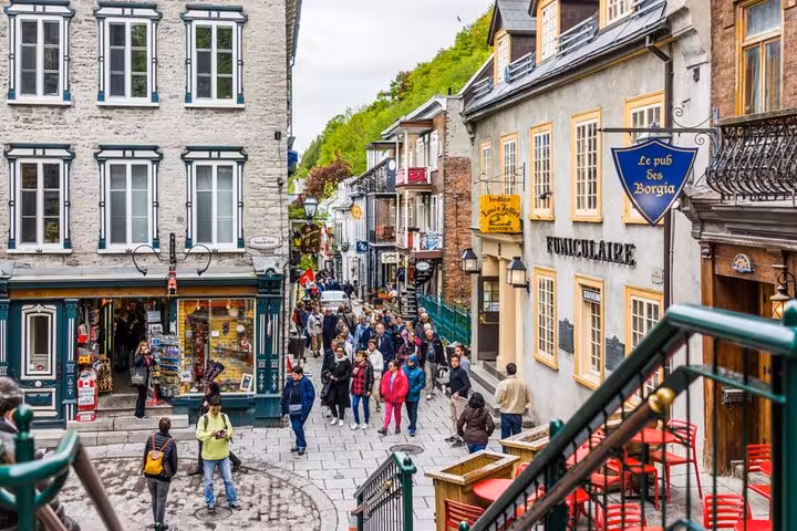 Busy pedestrian street in Old Quebec City with historic stone buildings, shops, and the Funiculaire sign