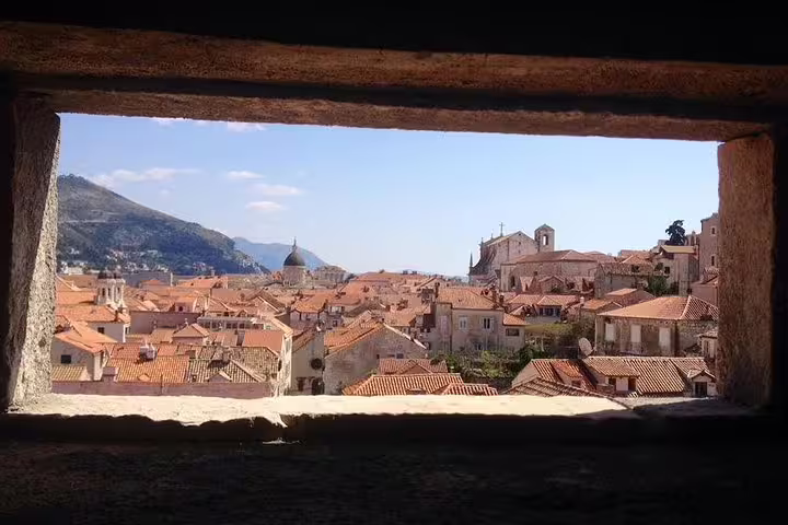 Panoramic Old Town rooftops framed by a stone window, scenic viewpoint on the Discover the Old Town Walking Tour