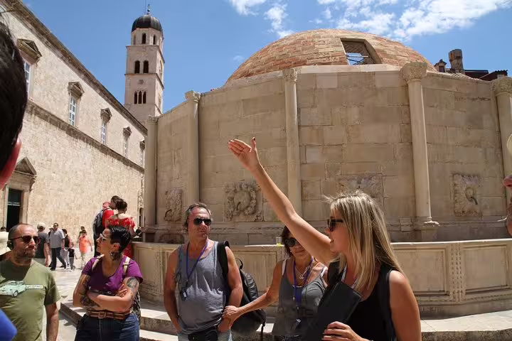 Tour guide explaining landmarks on Discover the Old Town Walking Tour beside Old Town fountain and bell tower
