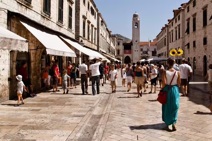 Crowds strolling Old Town main street on Discover the Old Town Walking Tour with cafés and clock tower views