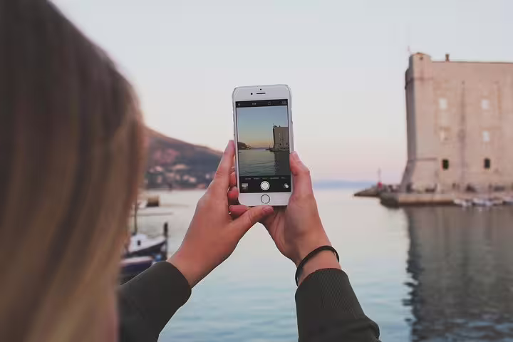 Traveler photographing the waterfront fortress at sunset, a highlight on the Discover the Old Town Walking Tour