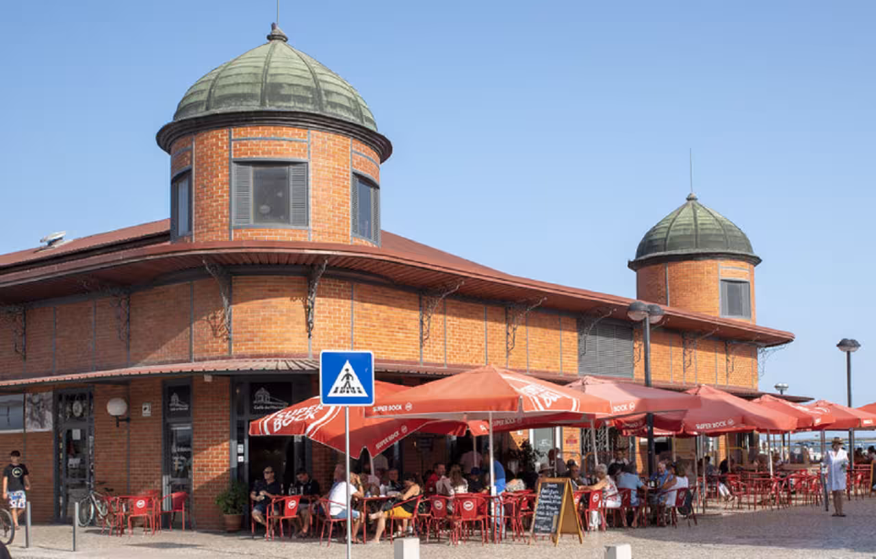 Café terraces under red umbrellas at Olhão Municipal Market, a highlight of full-day Eastern Algarve tours in Portugal