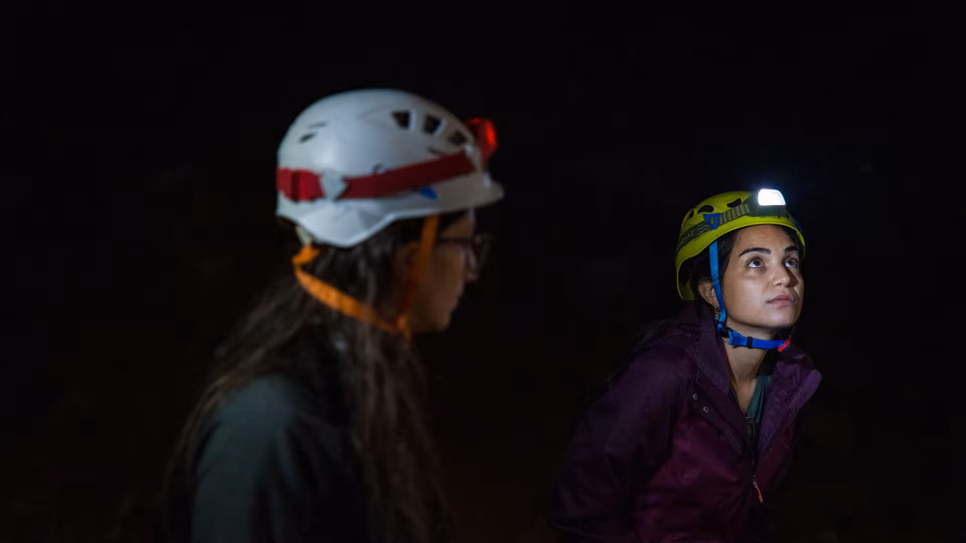 Close-up of explorers with helmets in the dark depths of Sa Nurre de Su Hoda cave, Oliena.