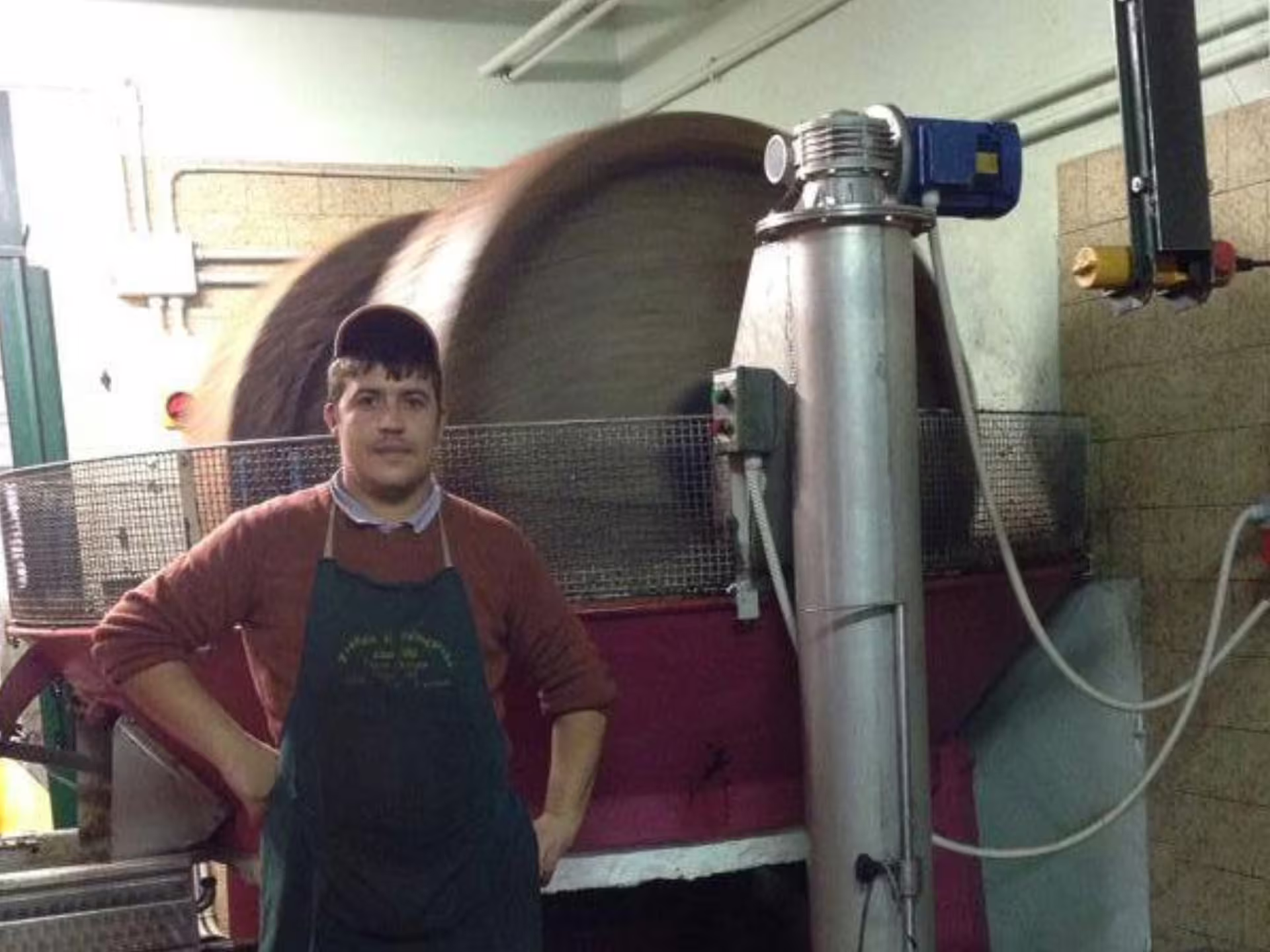 Local producer beside traditional olive mill machinery during Padua Hills olive oil tour, showcasing cold-press process