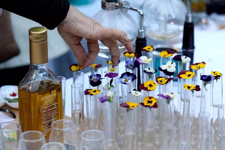 A variety of colorful edible flowers in test tubes next to a bottle of olive oil during a tasting event in Cordoba.