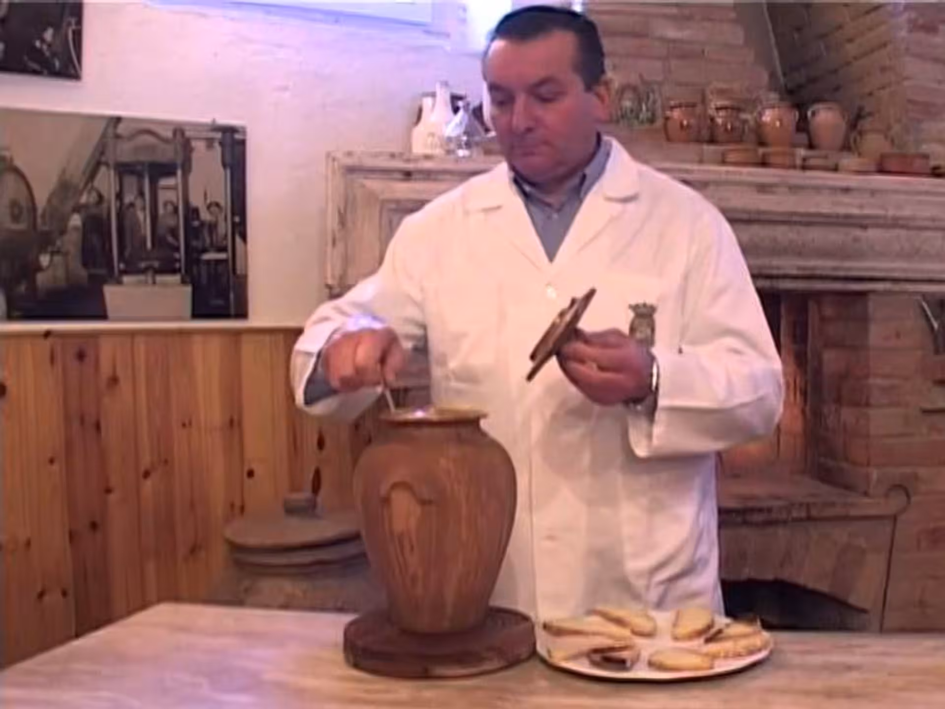 Man in a white coat sampling olive oil from a rustic container at a Perugia mill tasting event.