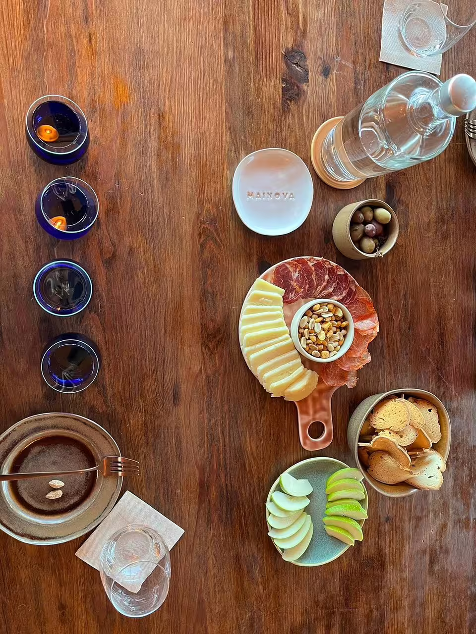 Assorted olive oils, cured meats, cheeses, nuts, and fresh fruits beautifully arranged on a rustic wooden table for tasting experience.