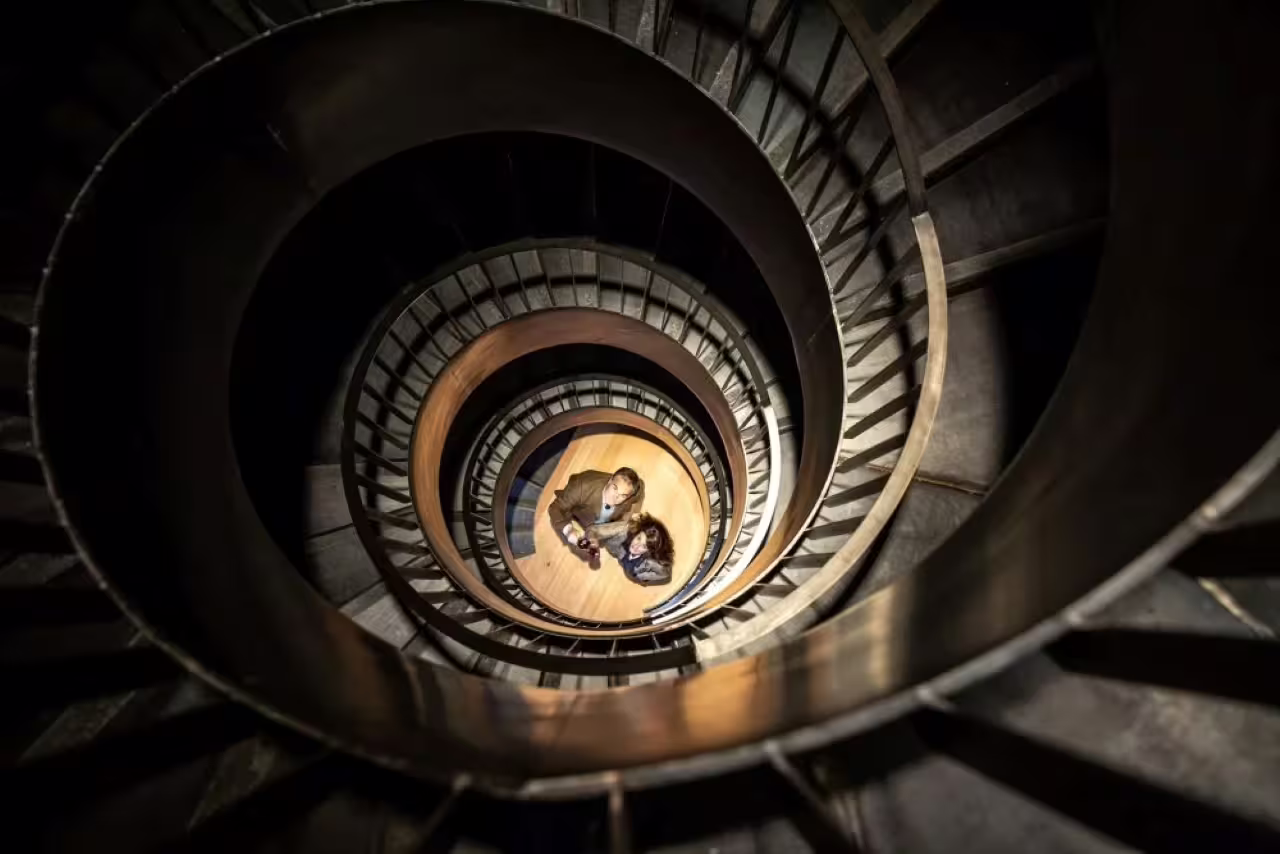 Spiral staircase view inside Oltrepò Pavese winery, guests looking up during guided cellar tour and wine tasting