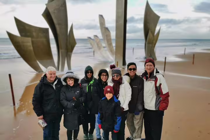 Group photo at Omaha Beach with Les Braves D-Day memorial, on a private Normandy landing beaches day tour from Paris