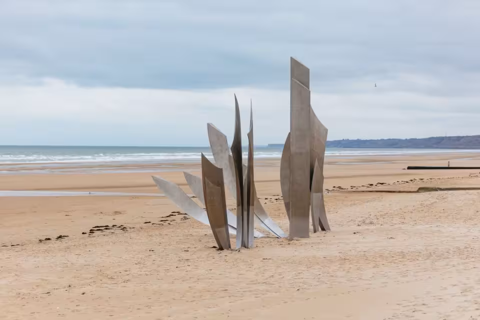 Steel memorial sculpture on Omaha Beach, Normandy, with sandy shore and ocean in background