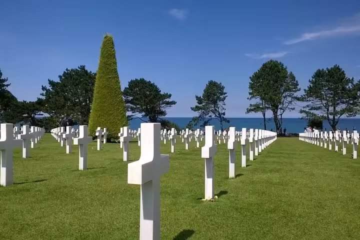 Rows of white crosses at Normandy American Cemetery overlooking Omaha Beach on a sunny day