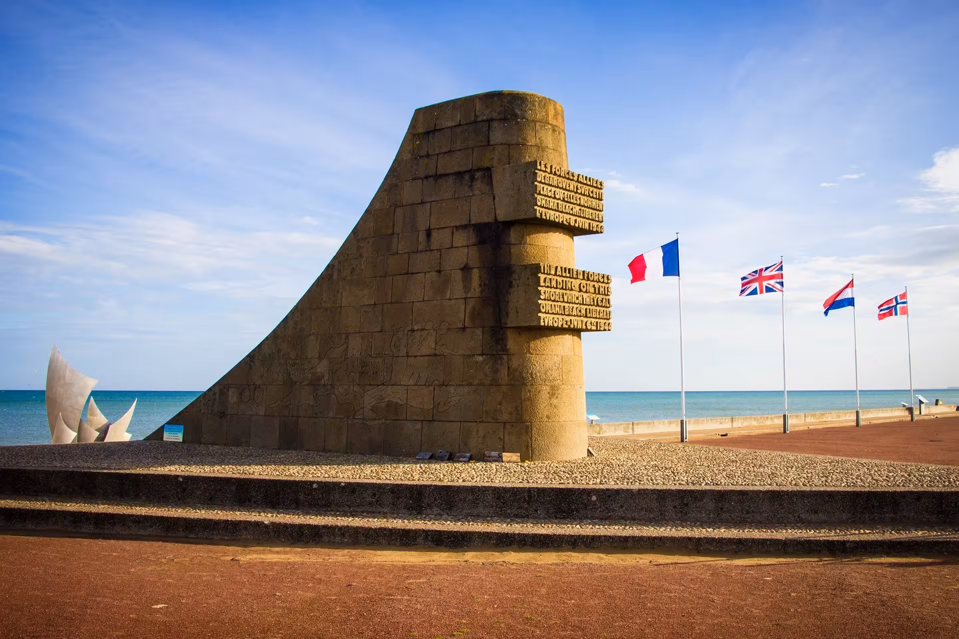 Omaha Beach D-Day memorial at Normandy coast with Allied flags, key stop on small-group luxury minivan tour