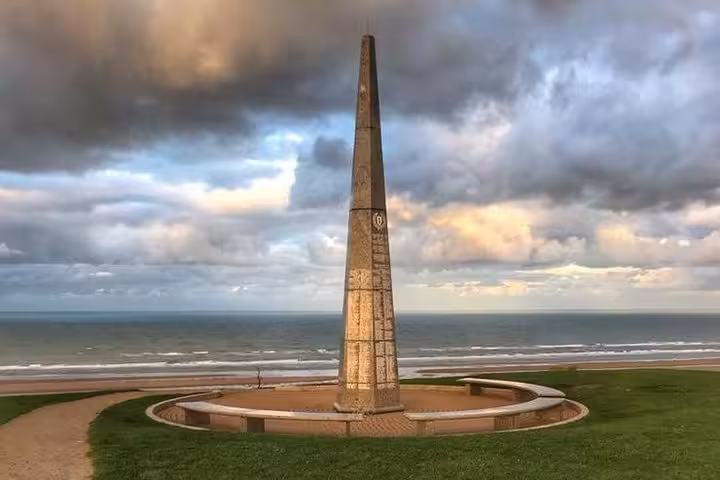 Stone obelisk memorial on Omaha Beach overlooking the English Channel on a cloudy day, Normandy