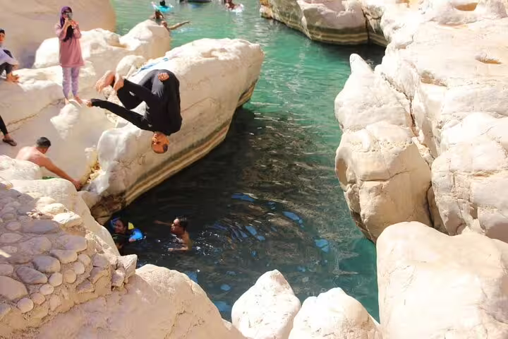 Adventurous cliff diving into turquoise waters at Wadi in Oman, showcasing excitement and natural beauty on private tour.