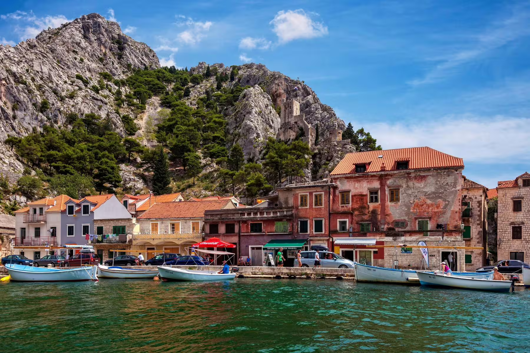Omiš waterfront with fishing boats and fortress cliffs, stop on River Cetina boat tour with lunch from Makarska