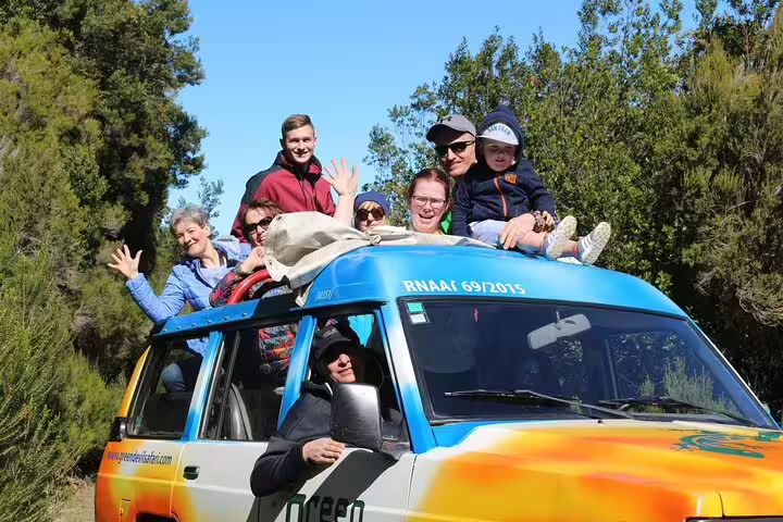 Group enjoying a scenic open-roof 4x4 adventure in the lush landscapes of Madeira's northwest, surrounded by vibrant greenery.