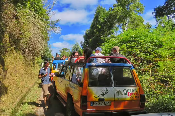 Tourists enjoy a scenic open-roof 4x4 adventure through the lush landscapes of Madeira's northwest under a clear blue sky.