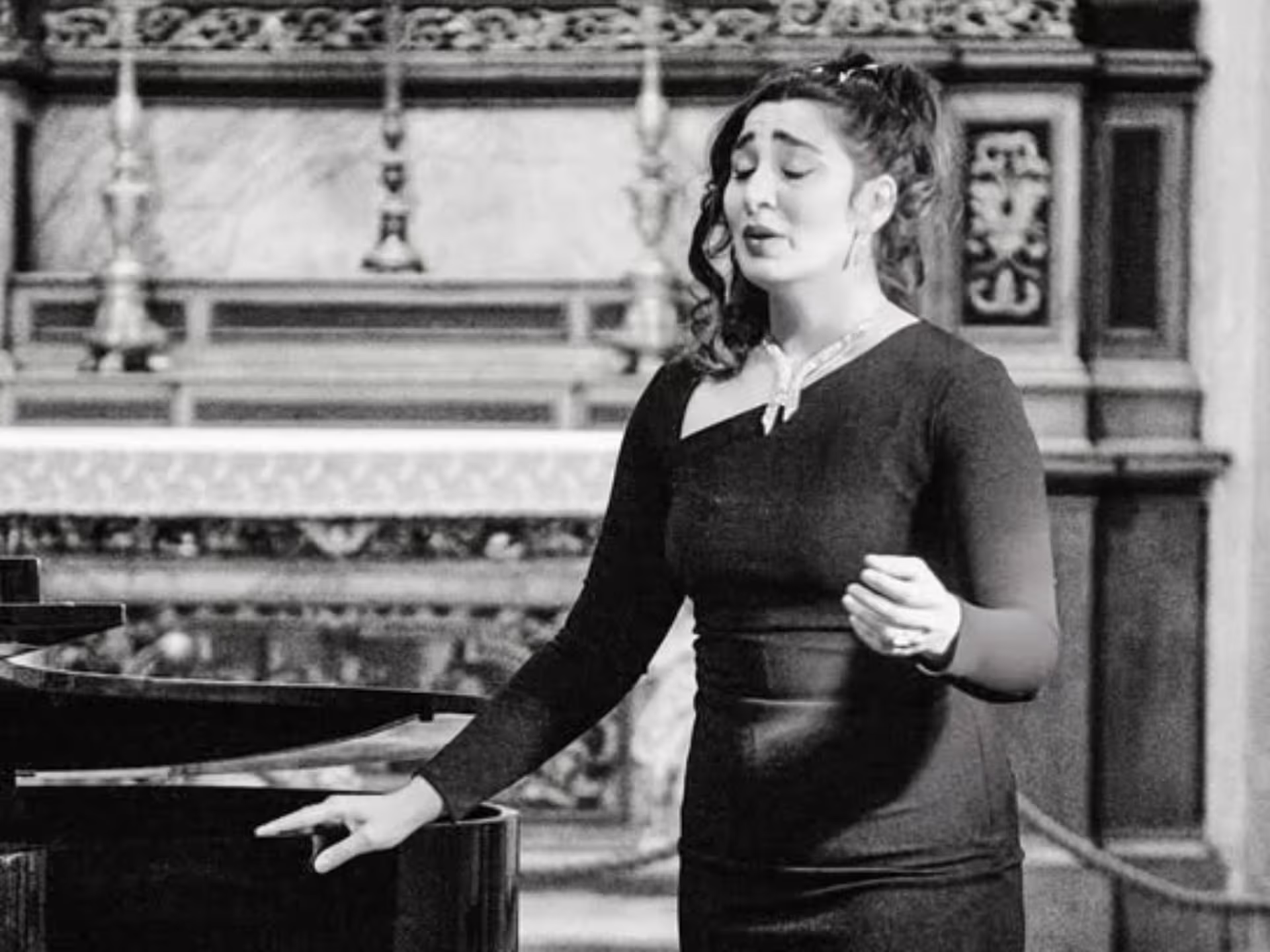 Black and white image of a solo opera singer expressing emotion during a performance at Verona Palace.