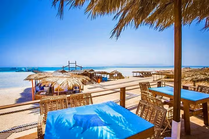 Orange Bay beach cafe with shaded tables and Red Sea view on full-day boat trip from Hurghada