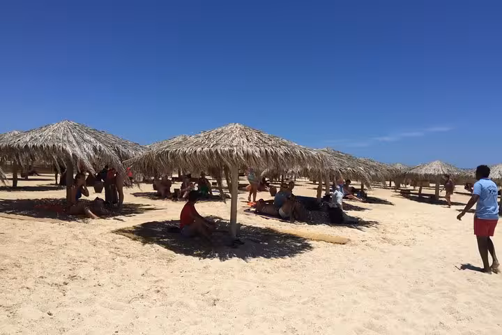 Orange Bay beach day trip from Hurghada with thatched umbrellas, soft sand lounging and clear Red Sea sky