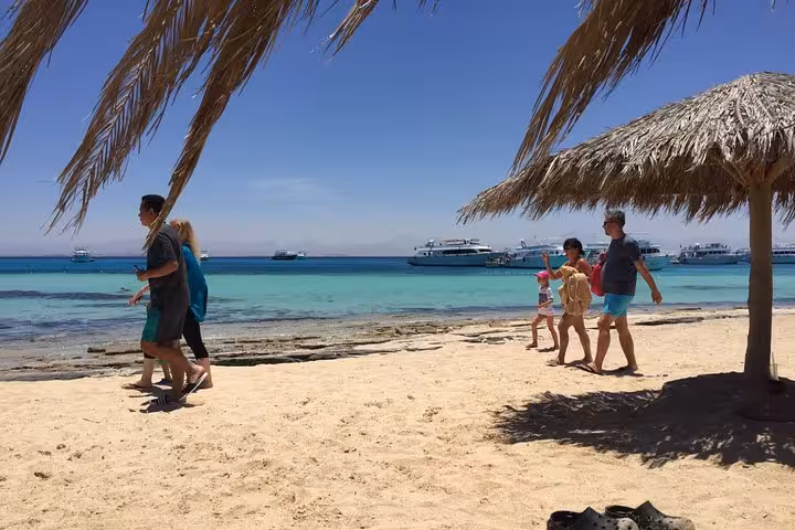 Orange Bay beach day trip from Hurghada with crystal-clear Red Sea water, shade huts, and families strolling