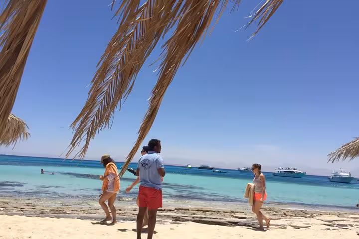 Orange Bay beach stop from Hurghada with turquoise Red Sea lagoon, sun shade palms and boats offshore