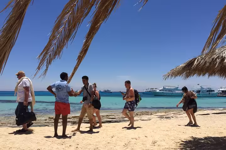 Guests arriving at Orange Bay from Hurghada, walking along turquoise shoreline with yachts on the Red Sea