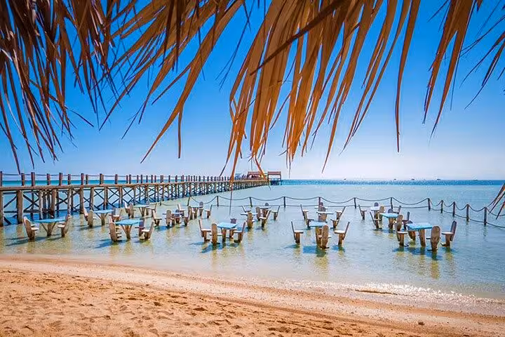 Orange Bay beach in Hurghada with wooden pier and shallow lagoon seating on a full-day boat trip