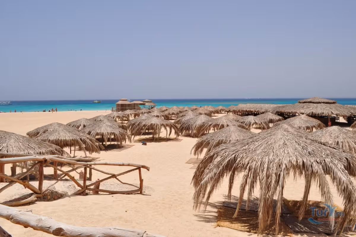 Orange Bay Island Egypt beach with straw umbrellas, soft sand and turquoise Red Sea waters on a Hurghada day trip