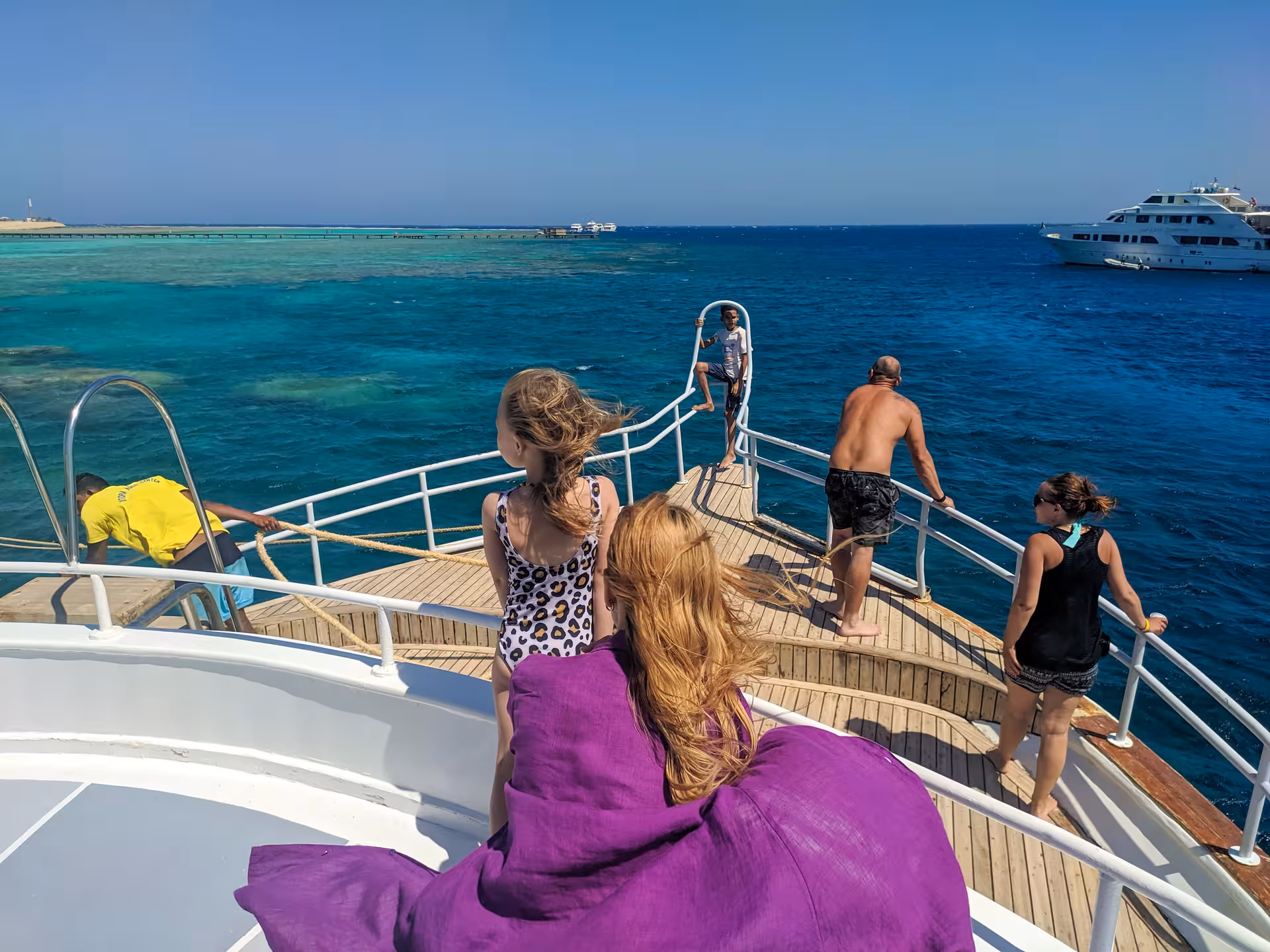 Guests on boat deck cruising to Orange Bay Island, Hurghada, with turquoise Red Sea snorkeling stops