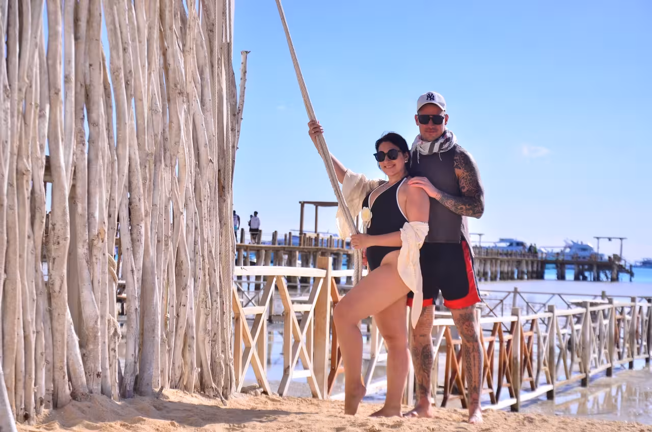 Couple posing on Orange Bay Island beach near wooden pier, Hurghada snorkeling excursion with lunch and boat ride