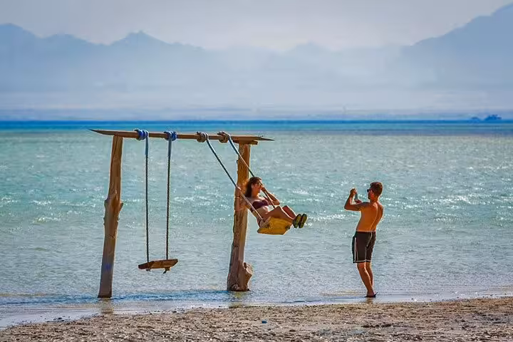 Couple enjoying the famous Orange Bay sea swing, part of a full-day Orange Bay tour from Hurghada